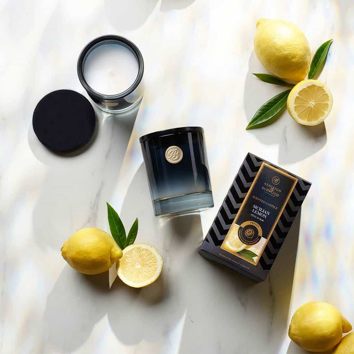 Sicilian Lemon Scented Candle on a white background surrounded by lemons
