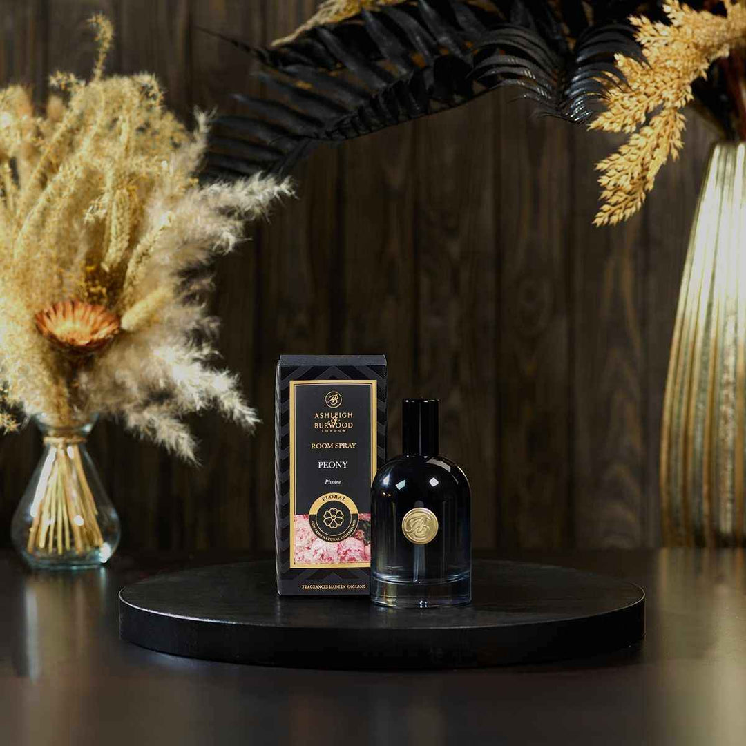 Peony Signature Room Spray next to its box against a dark background