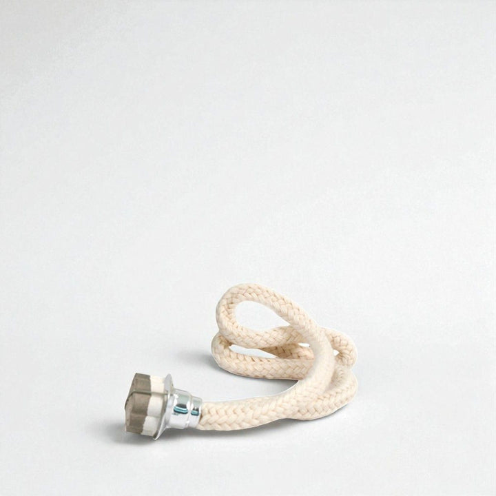 A loose large replacement wick against a white neutral background