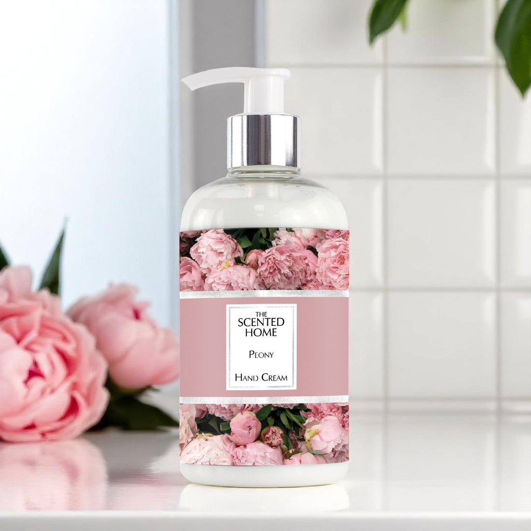 A bottle of Peony Hand Cream with a white tiled bathroom wall in the background, next to some peony flowers