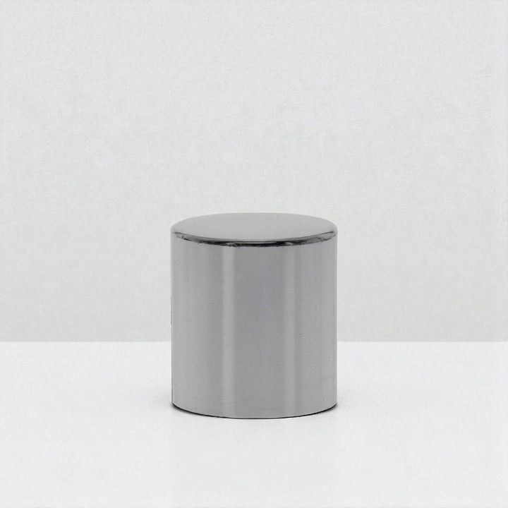 A large silver snuffer cap against a white neutral background