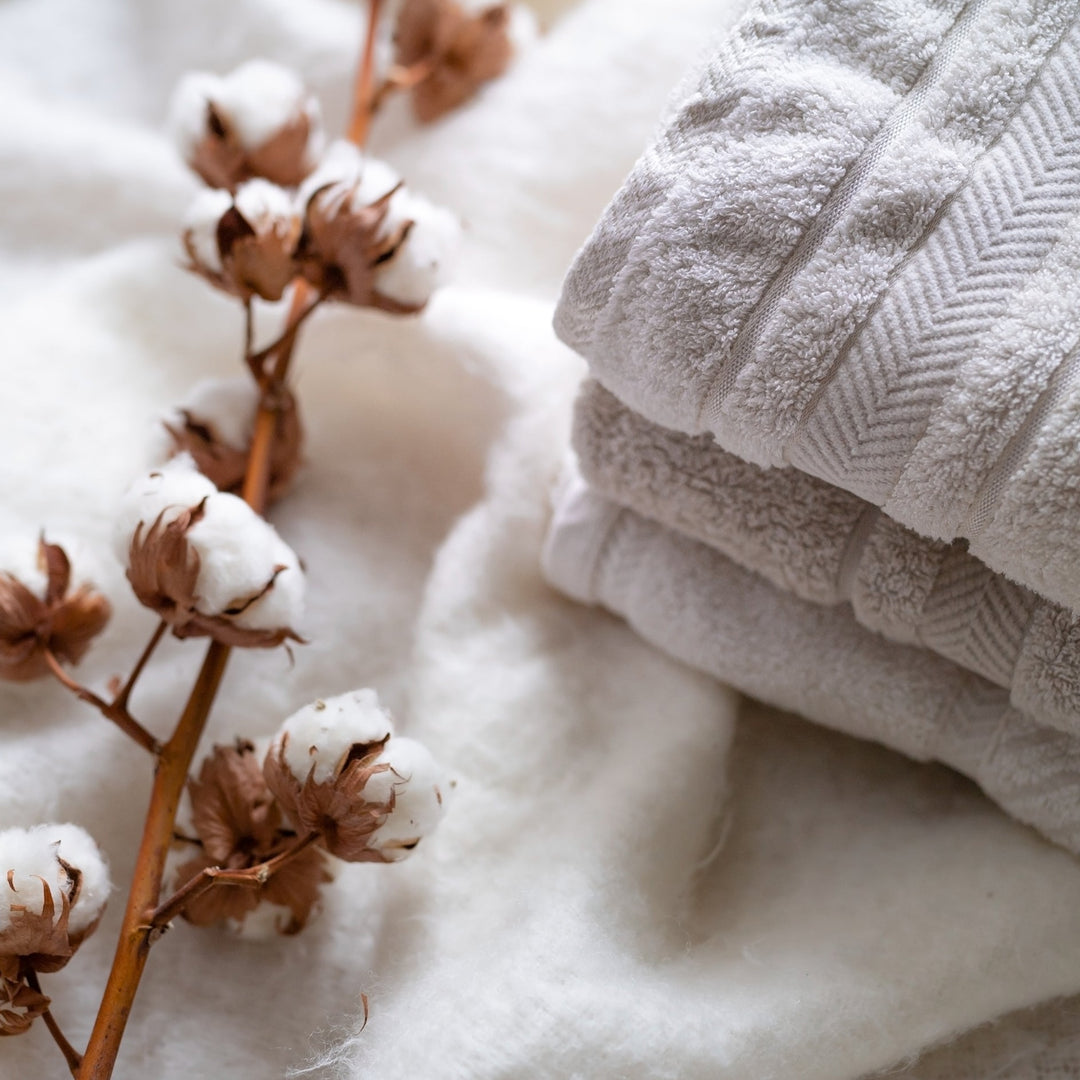 Cotton flowers lying next to a pile of fresh cotton towels