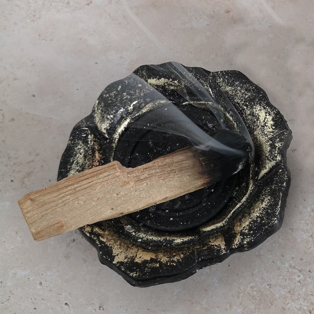 Stick of palo santo wood burning in a bowl