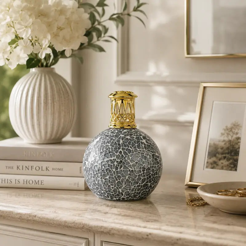 Decorative lamp with cracked texture on a surface with books and a vase in the background