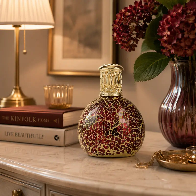 Decorative bottle with mosaic design on a table with books and a vase in the background