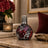 Decorative bottle with floral design on a table with books and flowers in the background