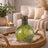 Decorative green mosaic lamp on a wicker tray with a living room background