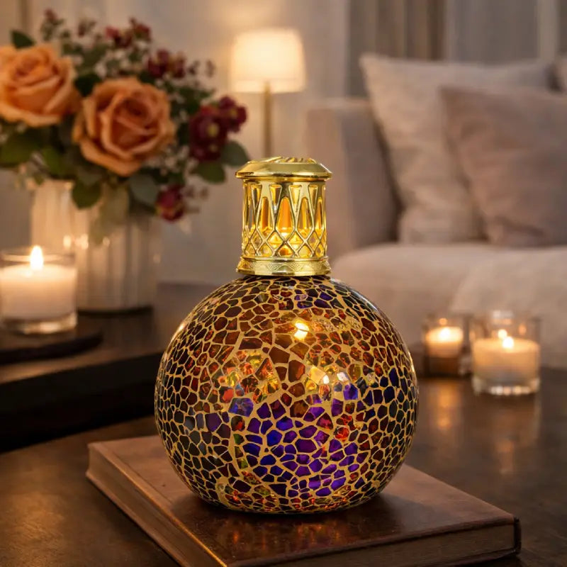 Decorative mosaic lamp on a table with candles and flowers in the background