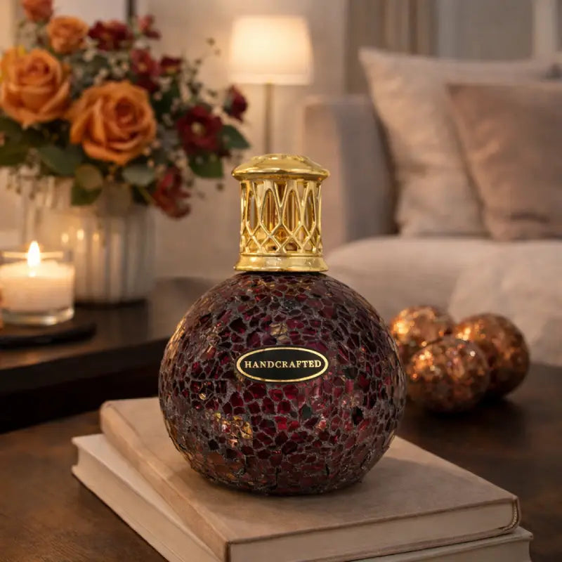 Decorative bottle with mosaic design and gold cap on a table with a cozy background