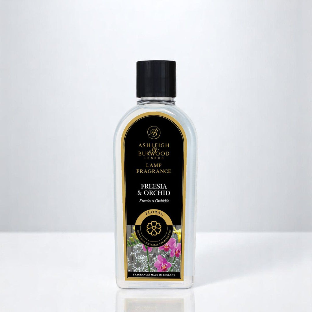 A bottle of Freesia & Orchid Lamp Fragrance against a white neutral background