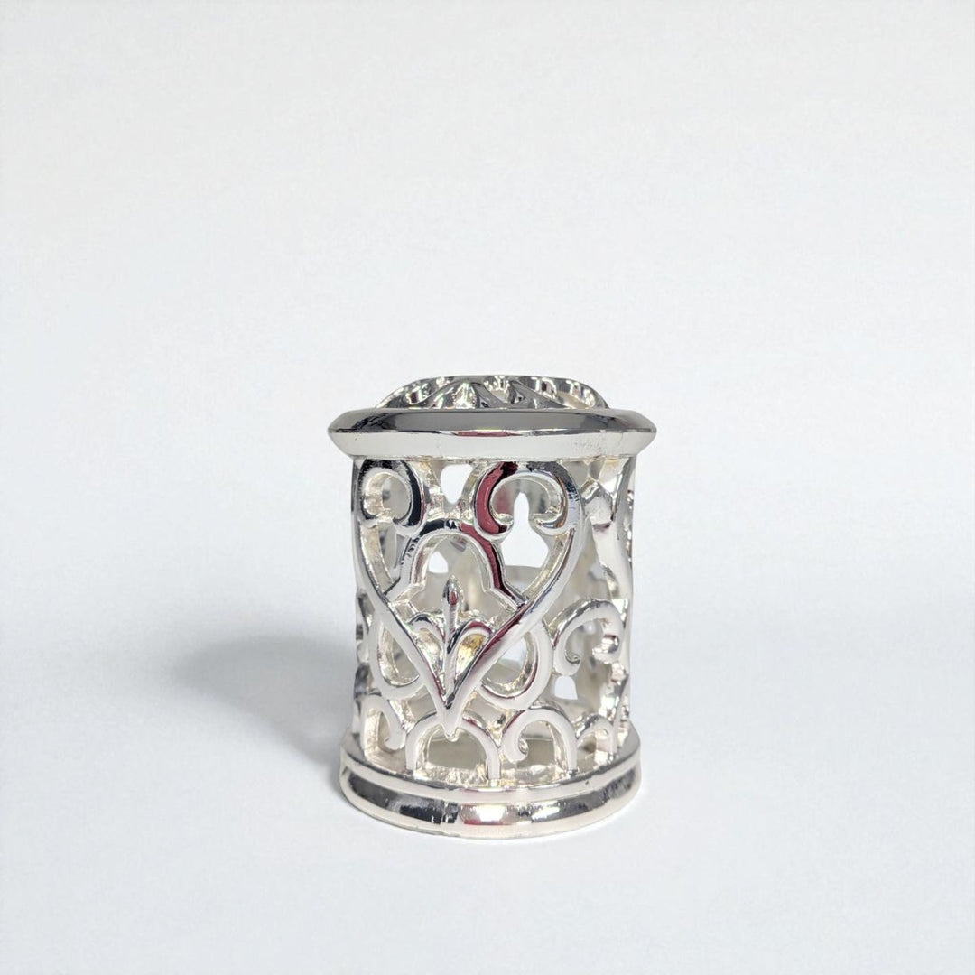 Silver thimble with intricate heart design on a white background