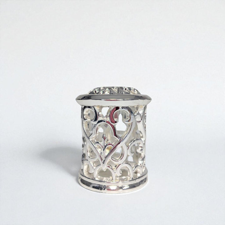 Silver thimble with intricate heart design on a white background