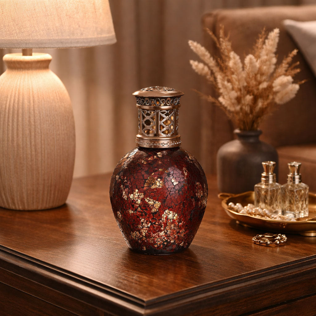 Decorative vase on a wooden surface with a lamp and plants in the background