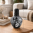 Decorative black and white vase on a wooden table with measurements indicated