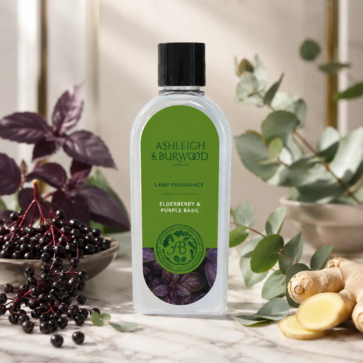A bottle of Ashleigh & Burwood London Elderberry & Purple Basil lamp fragrance, styled on a marble surface with fresh eucalyptus, purple elderberries, ginger, and a bowl of dark berries.