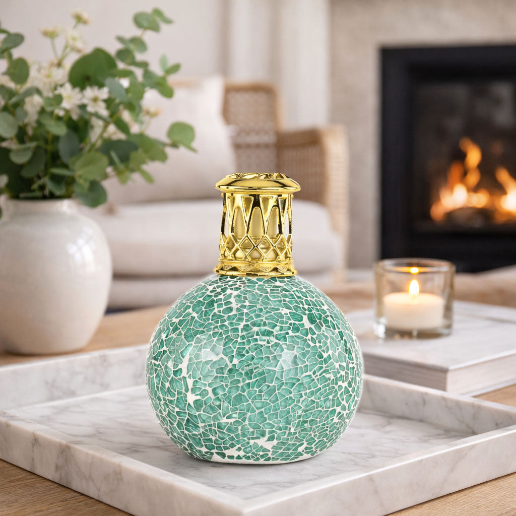 Decorative green vase with gold top on a marble surface in a cozy living room.