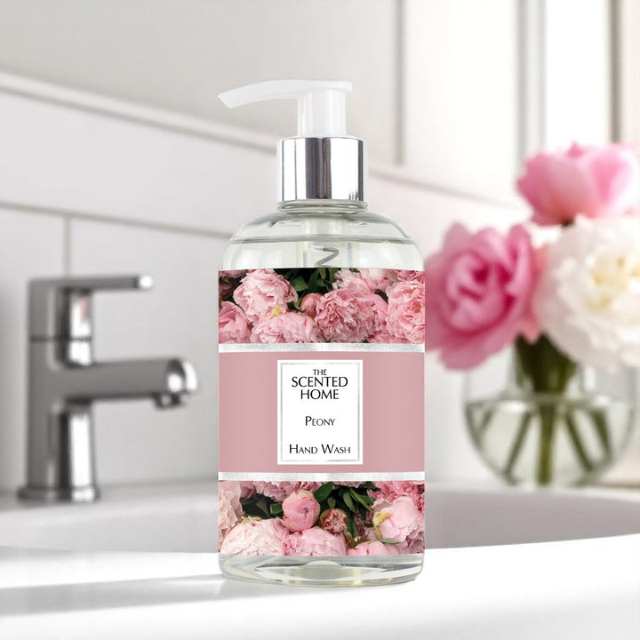 A bottle of Peony Hand Wash in a bathroom with peony flowers in a vase in the background