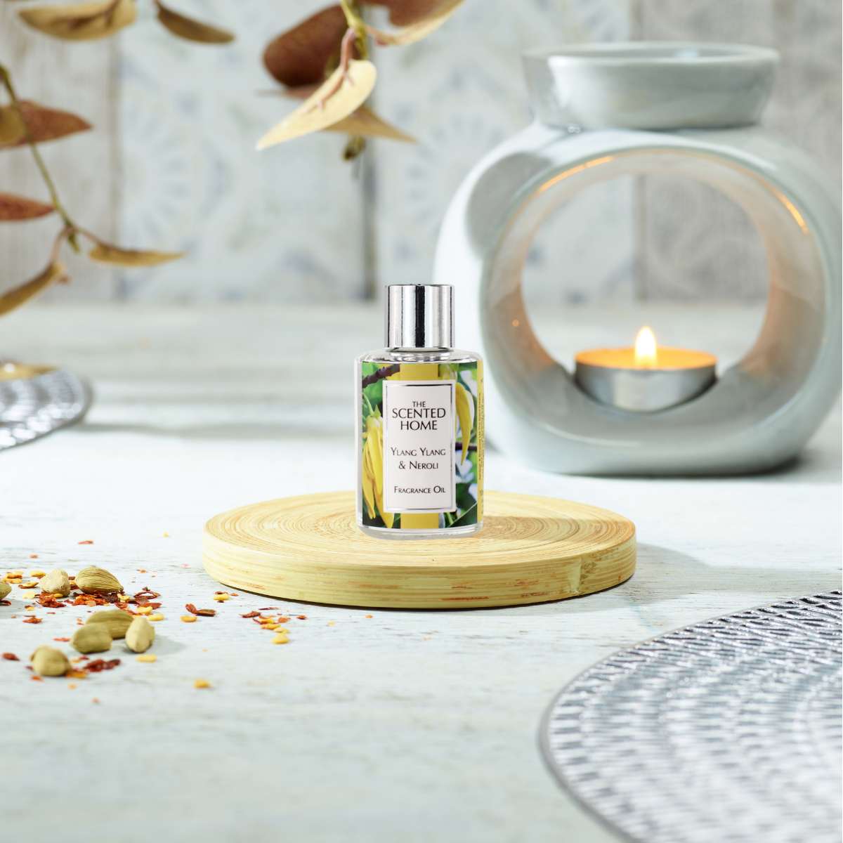 A picture of Ylang Ylang & Neroli Fragrance Oil on a wooden coaster with an Oil Burner in the background