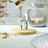 A bottle of Patchouli Fragrance Oil on a wooden coaster with an Oil Burner in the background