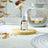 A bottle of Rose & White Oud Fragrance Oil on a wooden coaster infront of an Oil Burner