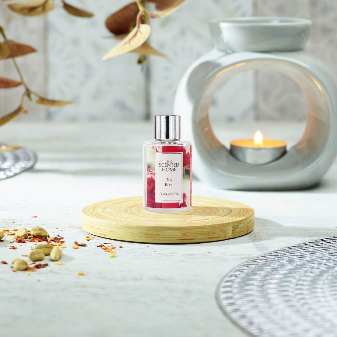 Tea Rose Fragrance Oil in the foreground with a lit Oil Burner in the background