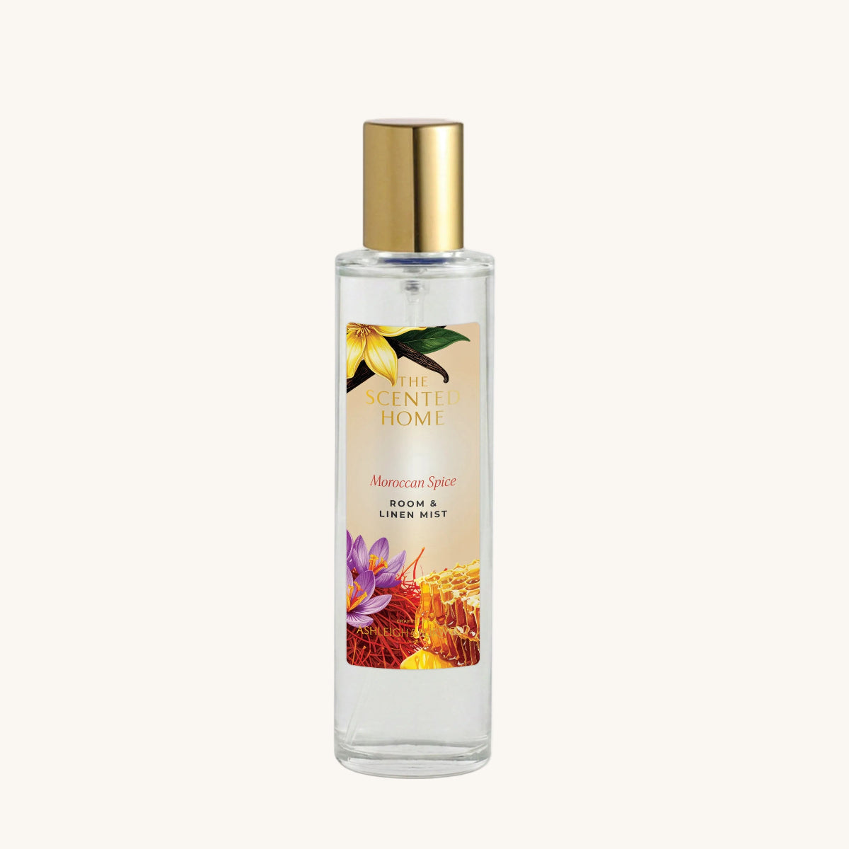 A clear glass bottle of 'The Scented Home' Moroccan Spice room and linen mist with a gold cap, set against a plain white background.