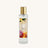 A clear glass bottle of 'The Scented Home' Moroccan Spice room and linen mist with a gold cap, set against a plain white background.