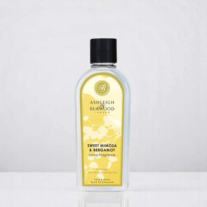 A bottle of Sweet Mimosa & Bergamot Lamp Fragrance against a white neutral background