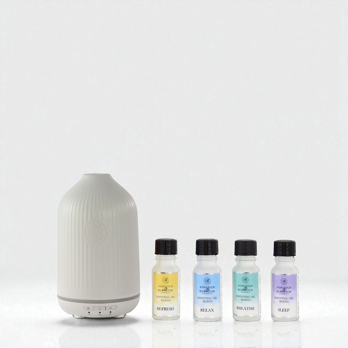 White diffuser with four small bottles of essential oils on a white background