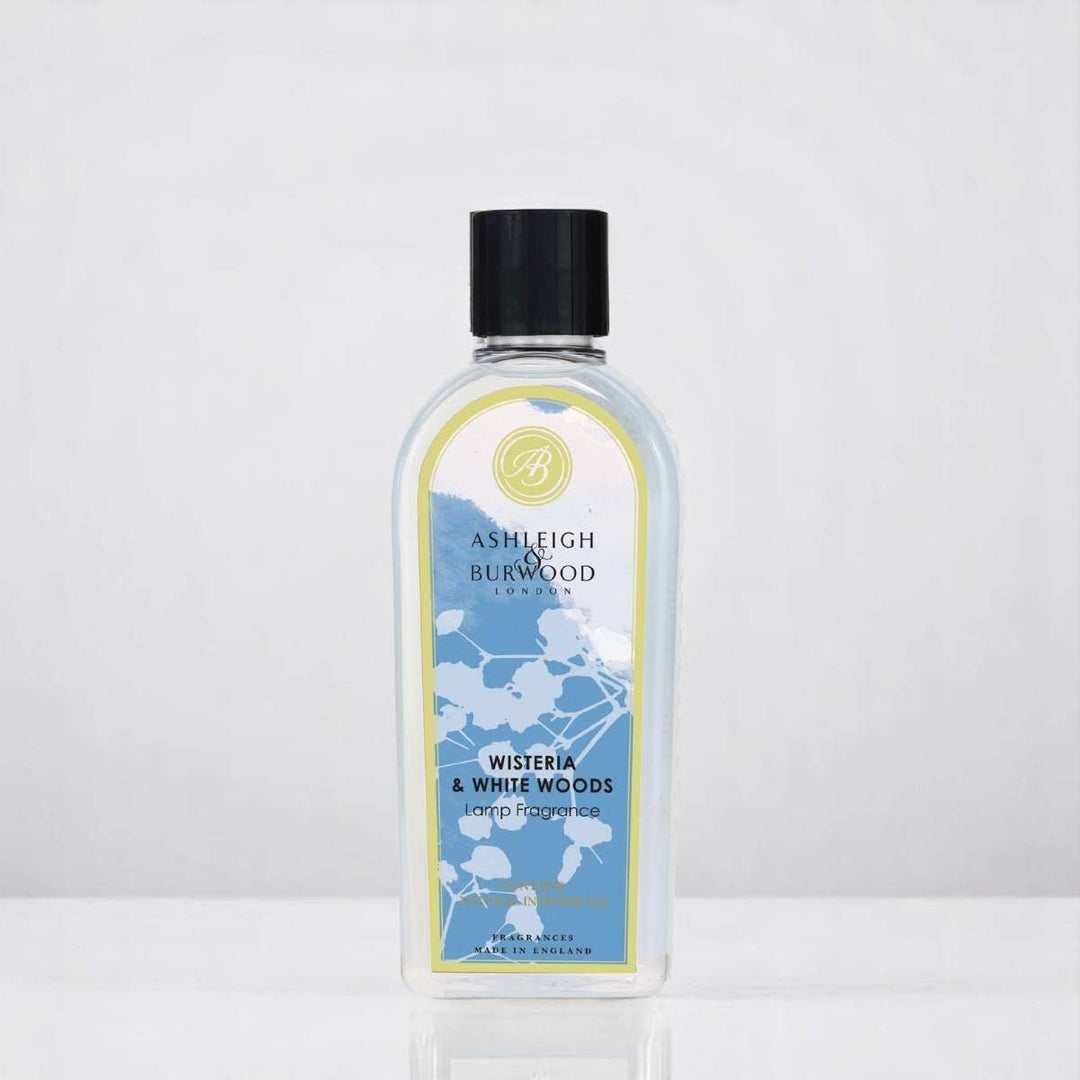 A bottle of Wisteria & White Woods Lamp Fragrance against a neutral background