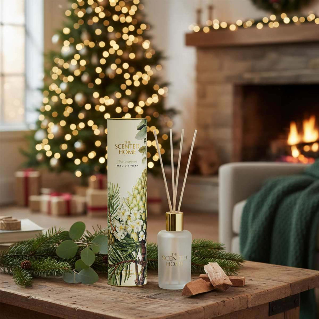 Scented home diffuser with packaging on a wooden table in a cozy living room with Christmas decorations.