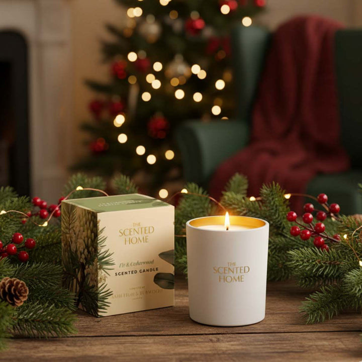 Candle and packaging with Christmas decorations on a wooden surface