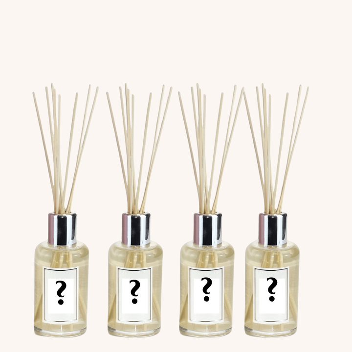 Four diffuser bottles with reeds and question mark labels on a white background