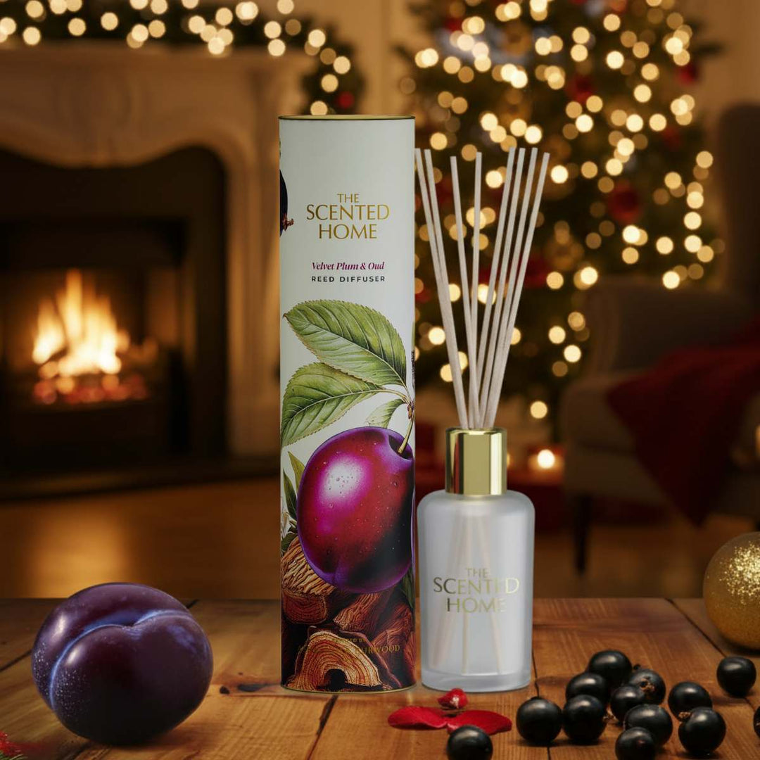 Reed diffuser with packaging on a table in front of a fireplace and Christmas tree.