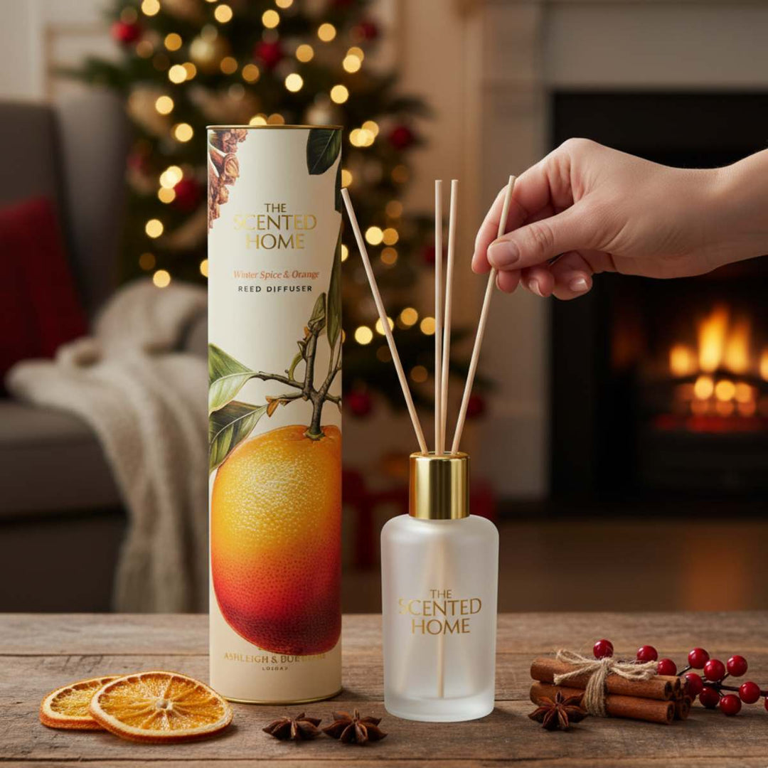 Reed diffuser with packaging and decorative elements on a table in a cozy room.